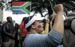 A protester gestures while wearing a South African flag over her head during a demonstration by the "March and March" movement. AFP/Rajesh Jantilal