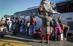Zimbabwean nationals line up carrying their belongings as they wait to board a bus at a Department of Home Affairs Refugee Reception Centre while awaiting repatriation. AFP/Rodger Bosch