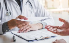  Doctor or physician writing diagnosis and giving a medical prescription to male Patient. Getty Images SARINYAPINNGAM