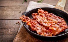 Hot fried crispy bacon slices in a skillet. GettyImages/LumenSt