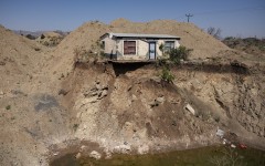 A house overlooks an open pit dug by illegal miners searching for chrome in Bapong