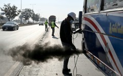 A technician examines a vehicle to test its emissions on road, at a checkpoint on the outskirts of Islamabad