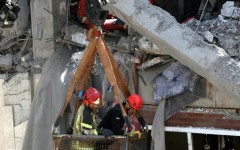 Firefighters try to recover the body of a victim in a damaged building in southern Tehran