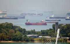 A container ship sails past oil tankers anchored in Singapore