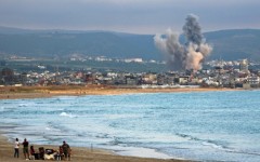 People visit beach against the backdrop of smoke rising from the site of an Israeli strike near the southern Lebanese city of Tyre on May 27