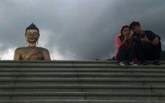 People look at a phone as they sit beside the Buddha Dordenma statue in Bhutan's capital Thimphu on August 25, 2018
