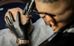 Tattoo artist Remy performing a scalp micropigmentation procedure on client Koki Hatanaka at his studio in Ginowan