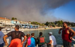 People use small boats to flee a wildfire near the village of Siviri, northern Greece