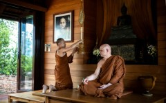 British and Thai Buddhist monk Shaun Chiverton, now known as Ajahn Jayasaro, sits as another monk holds a ceremonial fan in Bangkok