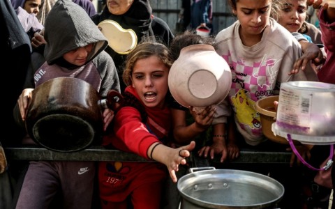 Displaced Palestinian children waited for food at a shelter in Nuseirat, Gaza, in November 2025