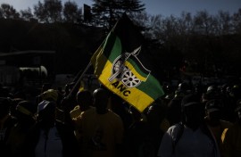 A man holds a flag of the South African ruling party African National Congress (ANC), as he gathers with supporters of former South African President Jacob Zuma outside House Hill building during the former South African president appearance at the Zondo Commission in Johannesburg, South Africa on July 15, 2019.