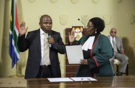 File: Des van Rooyen (L) raises his hand as he is sworn-in by Justice minister Sisi Khampepe as the new South African Finance Minister on December 10, 2015 at Union Builidngs in Pretoria, South Africa. 