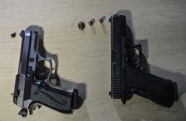 File: View of non lethal gun (L) and a 9mm pistol in a shooting range in Bogota, on September 17, 2021. Juan BARRETO / AFP