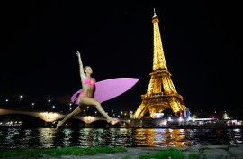 US surfer and adventurer Alison Teal jumps with her surfboard next to the Seine River in front of the Eiffel Tower in Paris.
