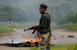 A soldier stands before a burning barricade during protests in Harare, Zimbabwe.