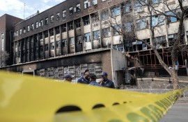 Police officers stand at the scene of the Joburg building fire. AFP/Luca Sola