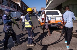 A private security guard carries his weapon as Johannesburg City Power employees move a large copper cable during an operation with the JMPD aimed to cut illegal power connection. AFP/Emmanuel Croset