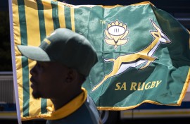 A hawker is seen in front of a South African Rugby team flag at an intersection in Melrose. AFP/Emmanuel Croset