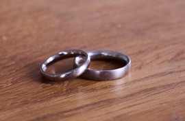 A pair of wedding rings lie on a wooden table. Annette Riedl/dpa Picture-Alliance via AFP