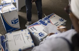 An election observer writes down notes as an IEC official tapes ballot boxes shut. AFP/Emmanuel Croset