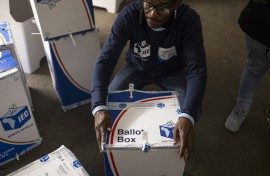 An IEC official tapes a ballot box shut in front of election observers. AFP/Emmanuel Croset