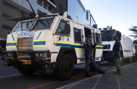 SAPS members stand next to an armoured police vehicle. AFP/Rodger Bosch