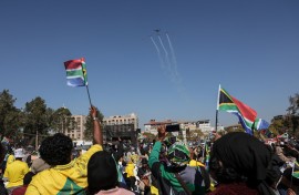 South Africans fly flags as they look at a flypast during President Cyril Ramaphosa's inauguration. AFP/Phill Magakoe