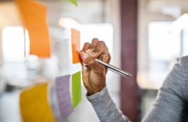 File: A woman/student writing on a sticky note. Getty Images/Luis Alvarez