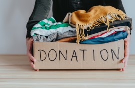 File: A woman holding a donation box filled with clothes. GettyImages/Damian Lugowski