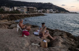 People sit on the rocks by the Mediterranean sea in Israel's northern coastal city of Haifa. AFP/Menahem Kahana