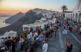Tourists take pictures of the sunset in the village of Fira on the Greek island of Santorini. AFP/Aris Oikonomou