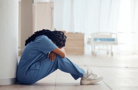 File: A nurse suffering from depression and burnout sitting on the floor. GettyImages/Jacob Wackerhausen