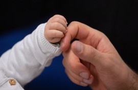 File: A father touches his child's hand during an infant handling course. Marijan Murat/dpa via AFP