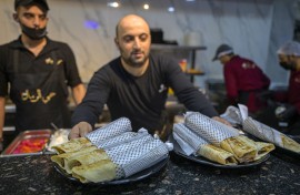 A waiter serves Gaza-style turkey shawarma sandwiches, wrapped in paper with the Kefiyeh pattern, at the 'Hay Al-Rimal' Palestinian-owned restaurant in Cairo. AFP/Khaled Desouki