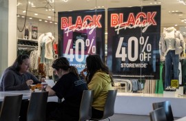 A family eats lunch near a store advertising a Black Friday sale at the Pentagon City Mall in Arlington. AFP/Andrew Caballero-Reynolds
