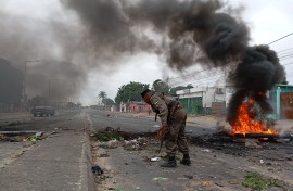 Mozambican security forces are seen next to a burning barricade in Maputo on December 24, 2024.