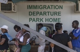 File: Zimbabwean migrants wishing to enter South Africa queue at a passport check before the immigration offices at the Beitbridge crossing. AFP/Marco Longari