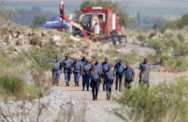 SAPS officers walk near a Metalliferous Mobile Rescue Winder during a rescue operation in Stilfontein. AFP/Christian Velcich