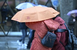 File: Pedestrians hide under an umbrella during a storm. Roberto Pfeil/dpa Picture-Alliance via AFP