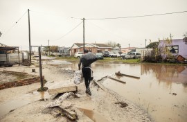 File: A man carries his belongings through flooded and damaged roads. AFP/Gianluigi Guercia