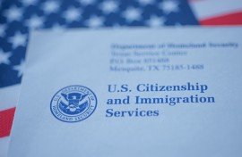A US citizenship letter from USCIS on a USA flag. GettyImages/Evgenia Parajanian