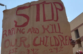 File: A protester holds a placard reading "Stop Raping and Kill(ing) our Children". AFP/Alexander Joe