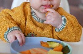 File: A baby sits at the table and reaches for different pieces of vegetables on a plate. Elisa Schu/dpa Picture-Alliance via AFP