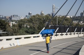 File: A man walks over a bridge connecting Alexandra to Sandton. AFP/Emmanuel Croset