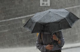 File: A person uses an umbrella to shelter from the heavy rain. AFP/Peter Parks
