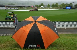 A fan shelters under an umbrella as the rain causes a delay during the fourth Twenty20 international cricket match between New Zealand and West Indies. AFP/Marty Melville