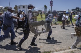 Riot police chase protesters from Dudula during a protest near the Nasrec Expo Centre. AFP/Ihsaan Haffejee