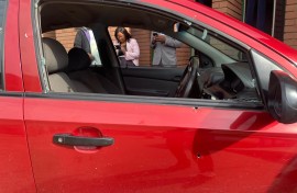 A red Chevrolet Aveo sedan, with a broken window.
