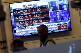 A television displaying market statistics is displayed as traders work on the floor of the NYSE. AFP/Timothy A Clary