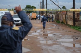 Police officers stand at the scene of an attack at a tavern in Bekkersdal. AFP/Emmanuel Croset